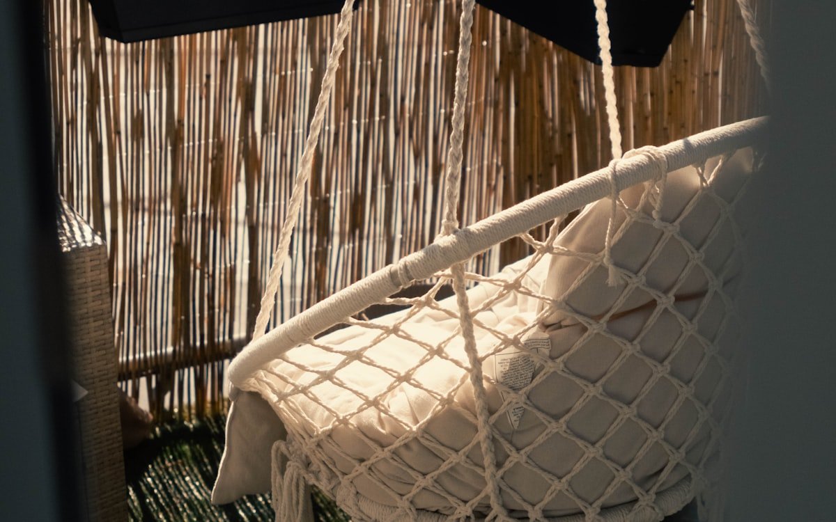 Terraza decorada en estilo bohemio con textiles y plantas colgantes