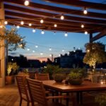Guirnalda de luces cálidas iluminando una terraza con mesa de comedor al anochecer