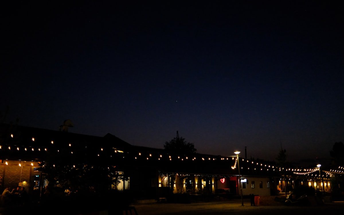 Terraza iluminada por la noche con varias fuentes de luz cálida