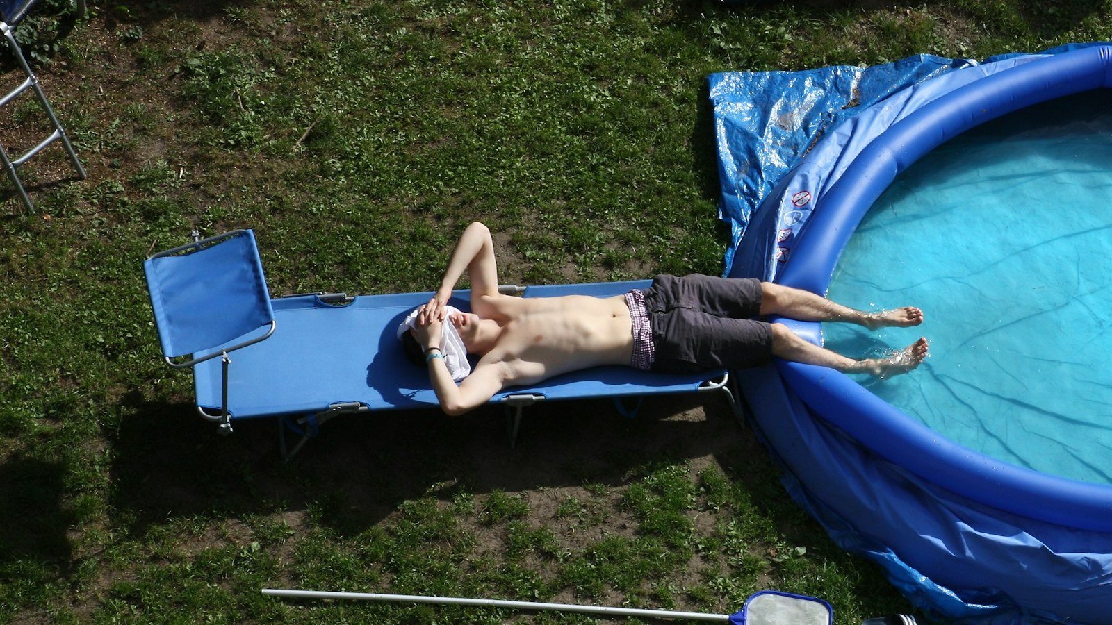 Piscina desmontable redonda con la lona cobertora doblada junto al borde en un jardín