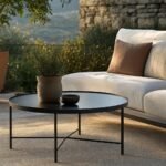 Mesa de centro redonda de exterior junto a un sofá en una terraza