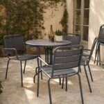 Sillas de exterior apilables de metal alrededor de una mesa en una terraza